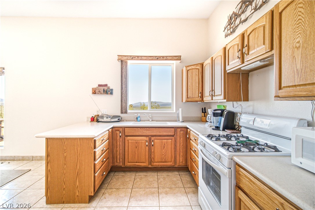 Rocking S Ranch Road Searchlight, NV 89046 - Photo 20 of 47 A well-lit kitchen with natural wood cabinetry and a functional U-shaped counter space.