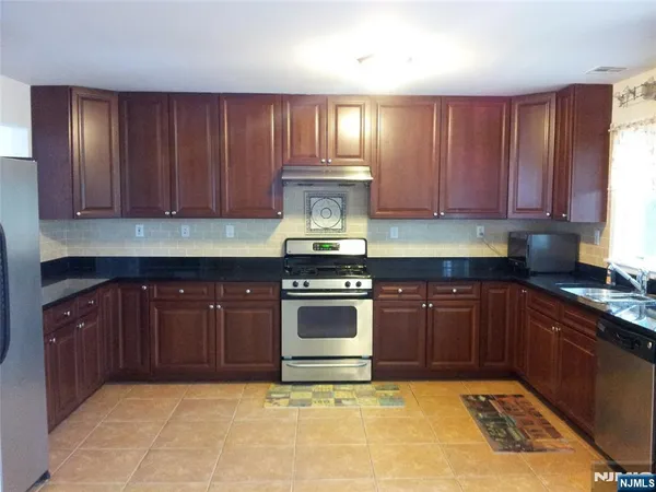 a kitchen with granite countertop stainless steel appliances stove top oven and cabinets