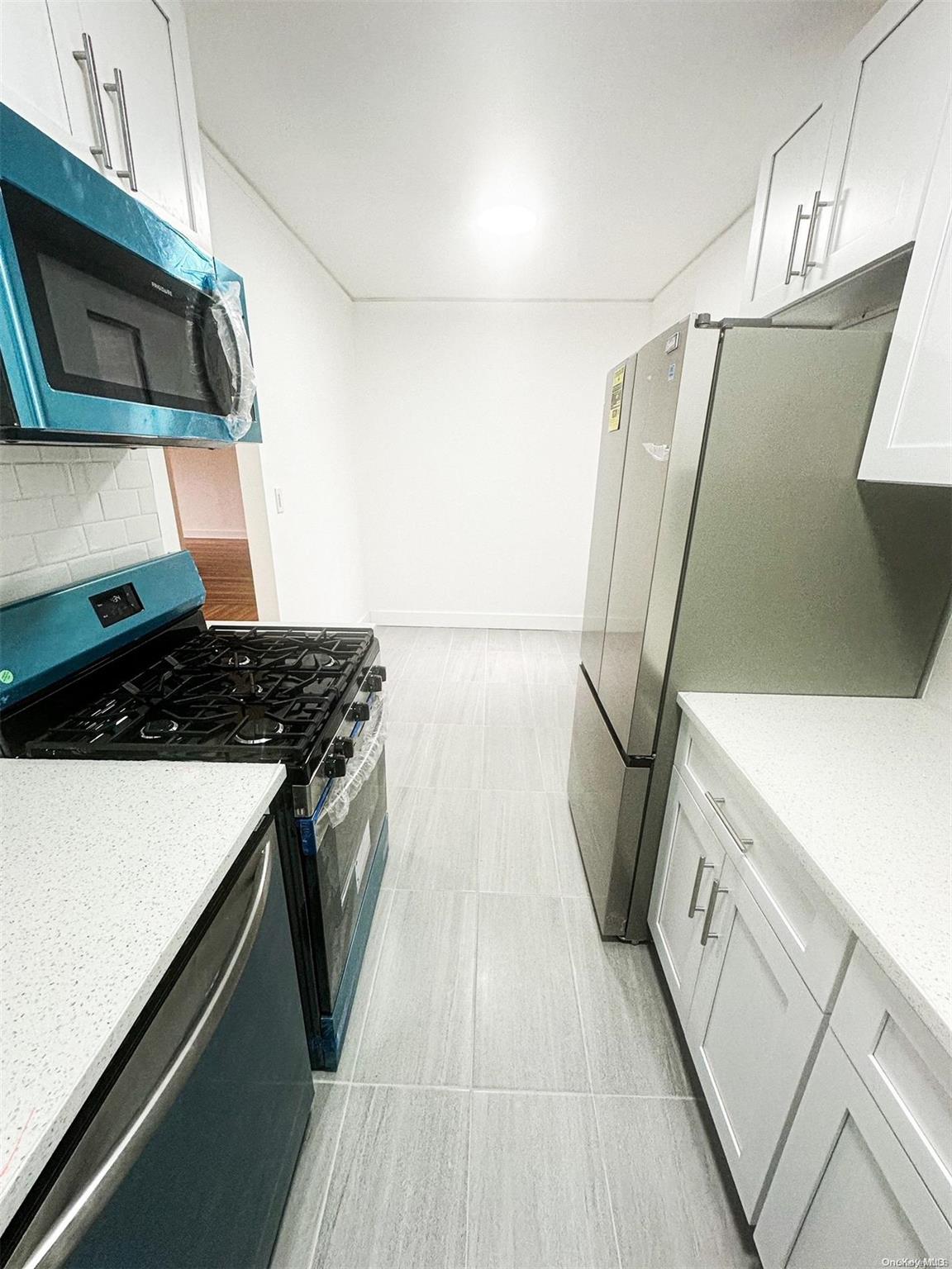 110-34 73rd Road, Unit 4C Queens, NY 11375 - Photo 3 of 10 a kitchen with stainless steel appliances granite countertop a stove and a microwave