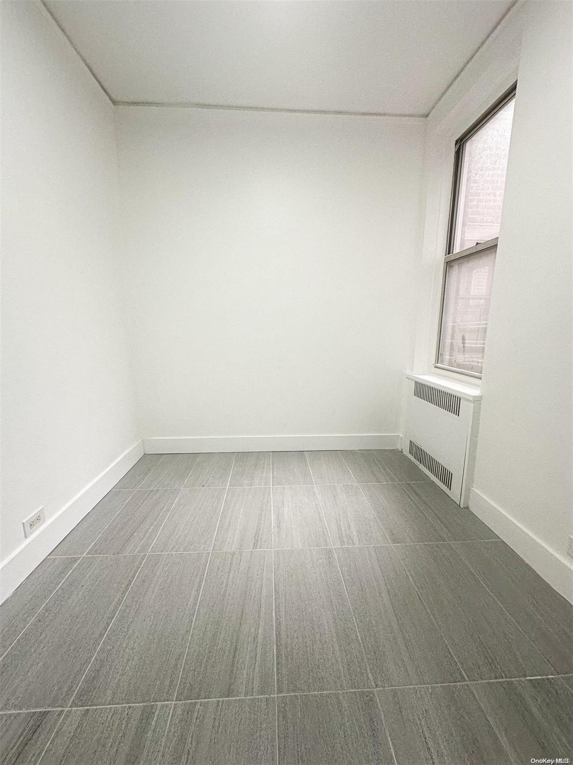 110-34 73rd Road, Unit 4C Queens, NY 11375 - Photo 4 of 10 an empty room with wooden floor and windows