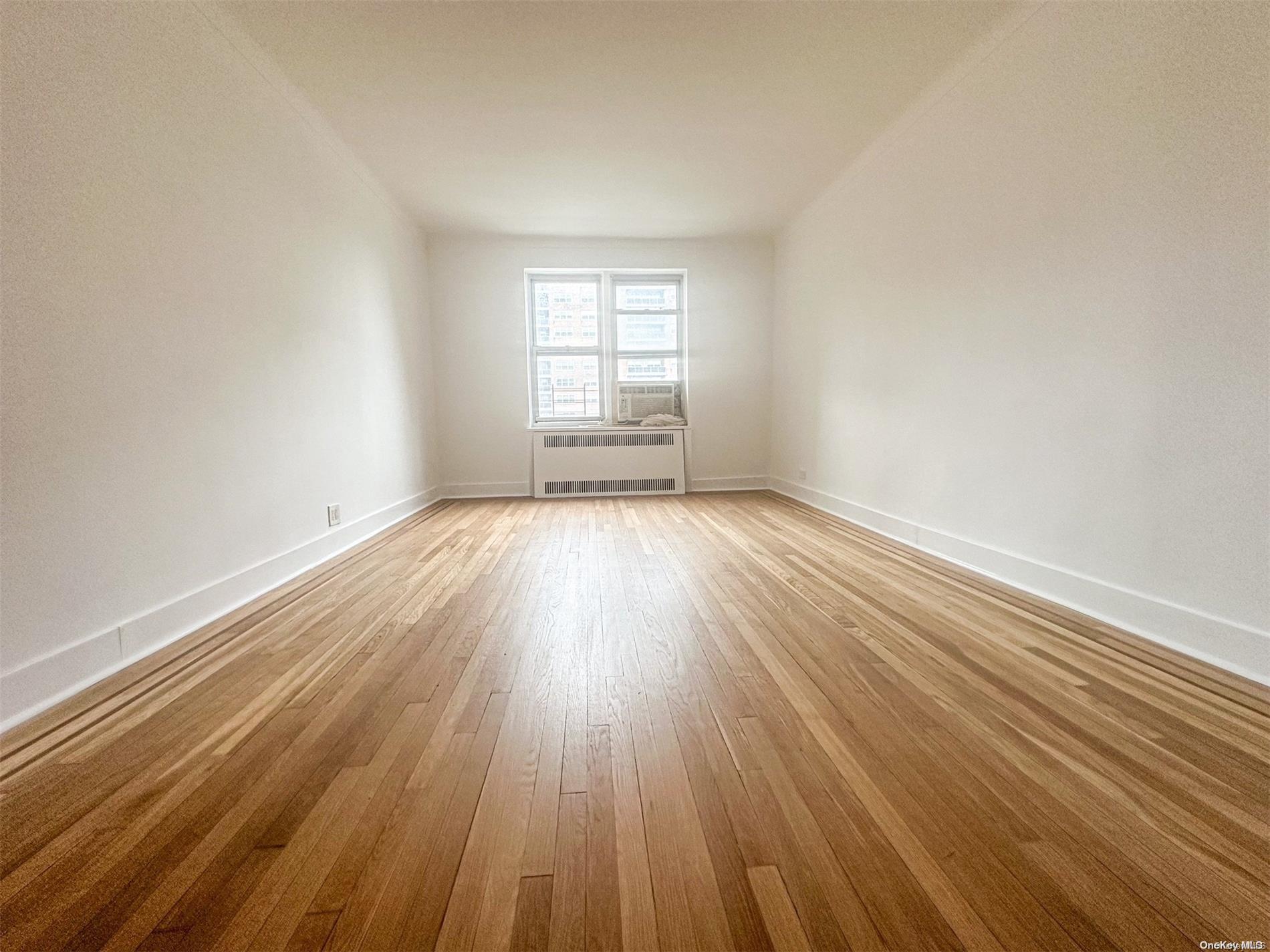 110-34 73rd Road, Unit 4C Queens, NY 11375 - Photo 6 of 10 a view of an empty room with wooden floor and window