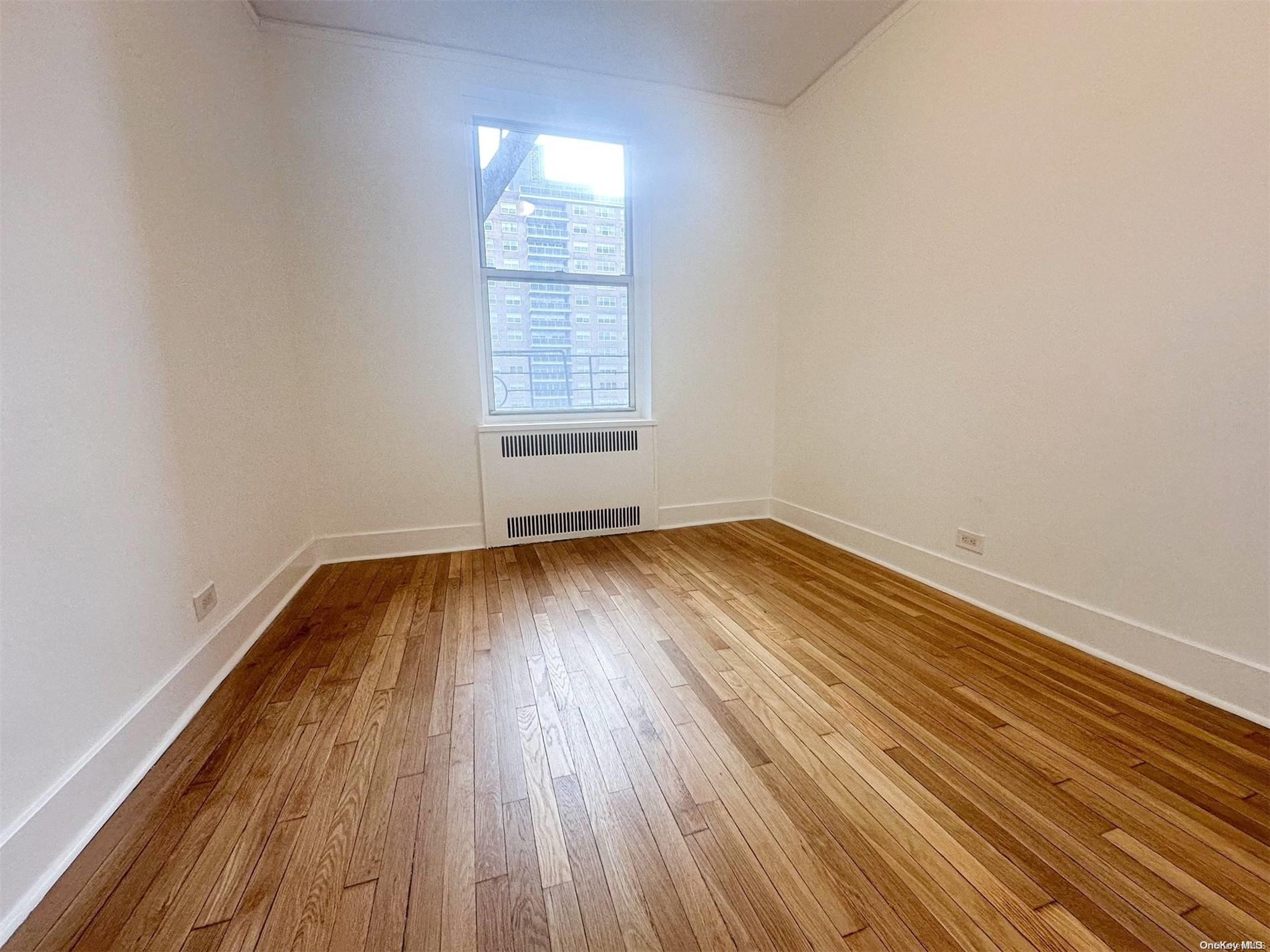 110-34 73rd Road, Unit 4C Queens, NY 11375 - Photo 10 of 10 an empty room with wooden floor and windows