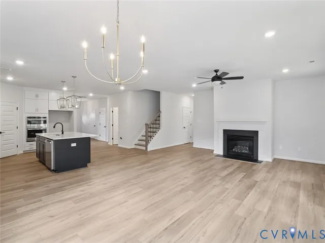 a view of kitchen with kitchen island a sink wooden floor and a fireplace