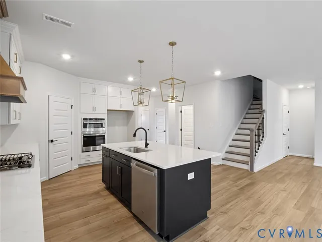 a kitchen with stainless steel appliances granite countertop a sink a stove and a refrigerator