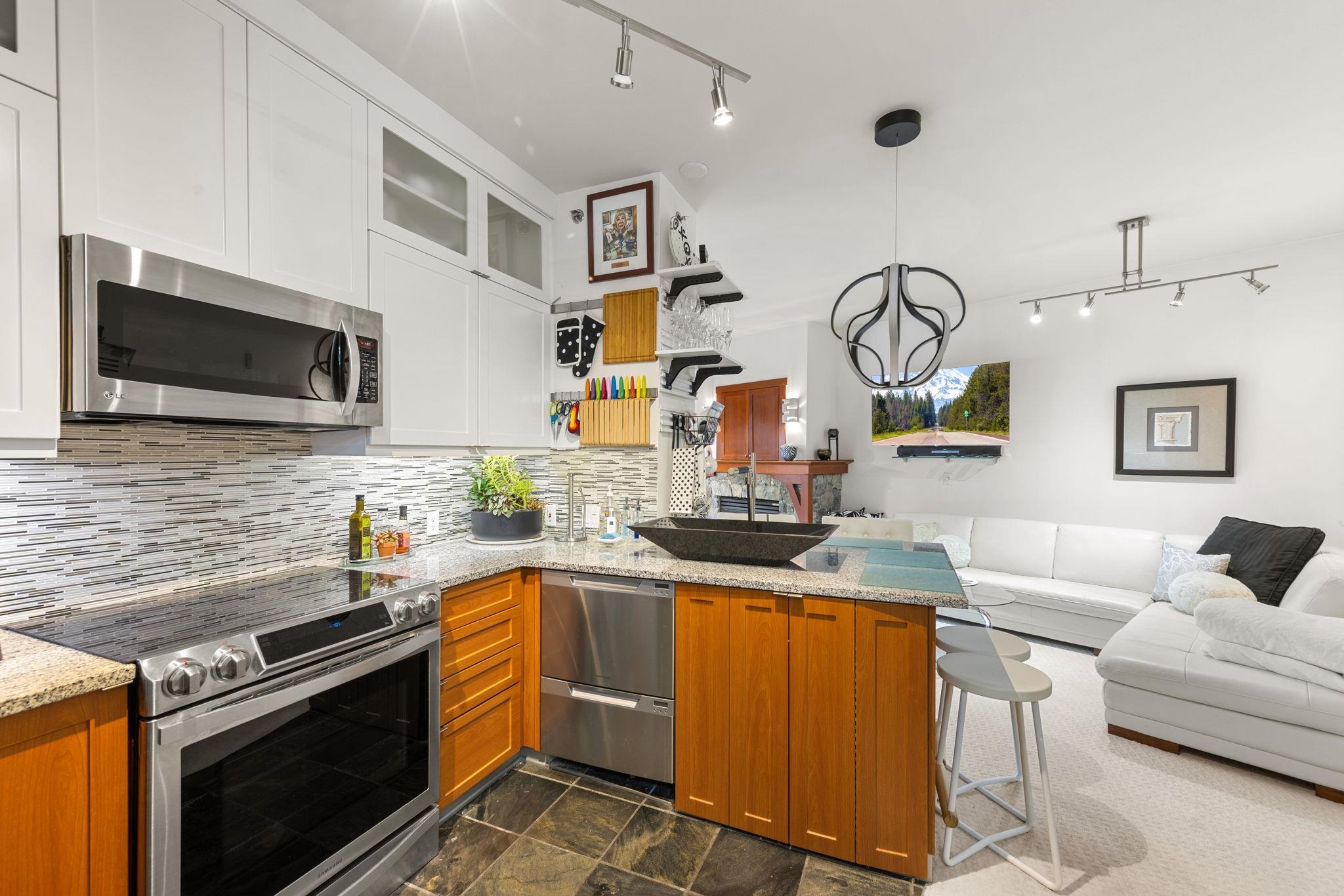 1750 Village East Road, Unit 409 (5409) Olympic Valley, CA 96146 - Photo 3 of 27 a kitchen with stainless steel appliances granite countertop a sink a stove top oven a chimney wooden floor and cabinets