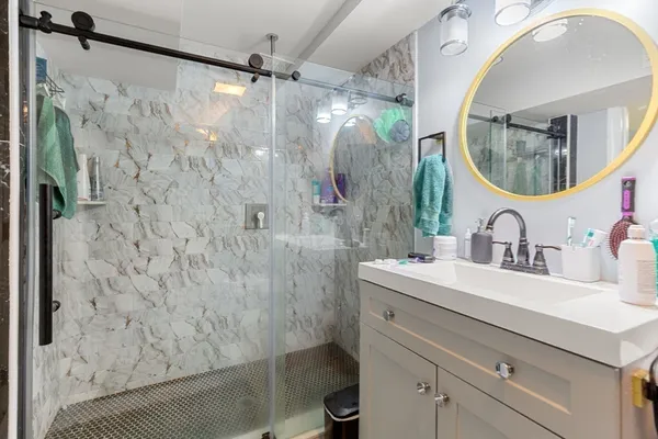 a bathroom with a sink a mirror a vanity and a shower