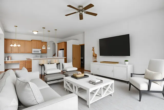 a living room with furniture a flat screen tv and kitchen view