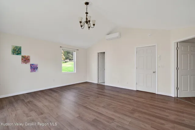 an empty room with wooden floor chandelier and windows