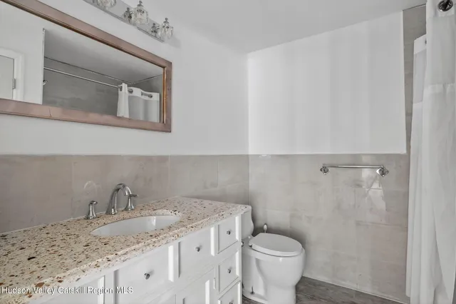 a bathroom with a granite countertop sink and a toilet