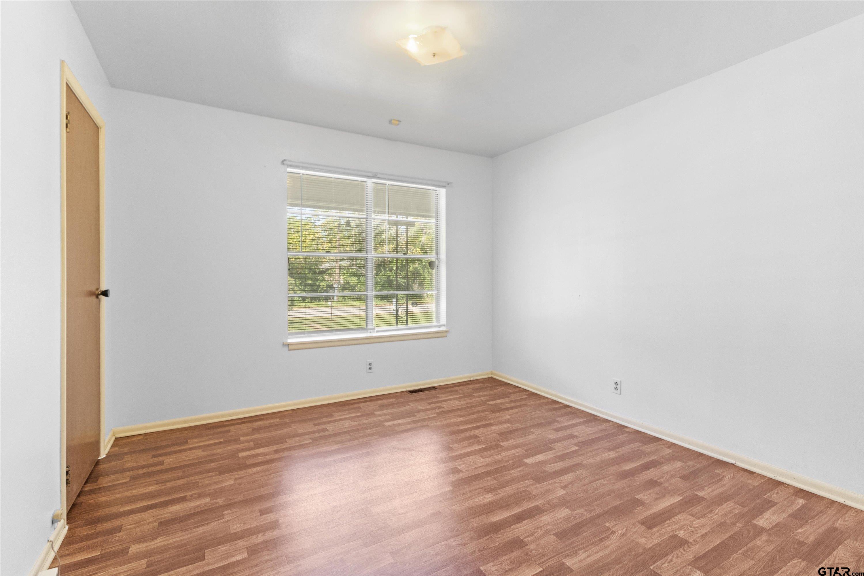 4168 Gallion Avenue Tyler, TX 75708 - Photo 12 of 27 an empty room with wooden floor and windows