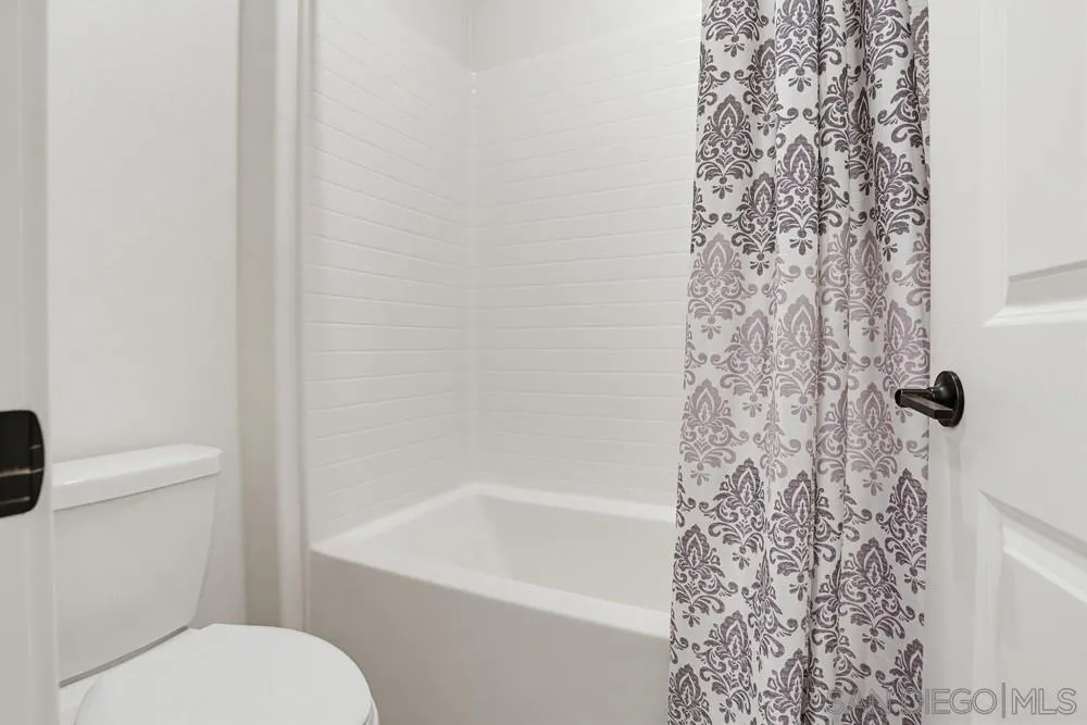 4373 Pacifica Way, Unit 6 Oceanside, CA 92056 - Photo 34 of 48 a white toilet sitting next to a shower curtain