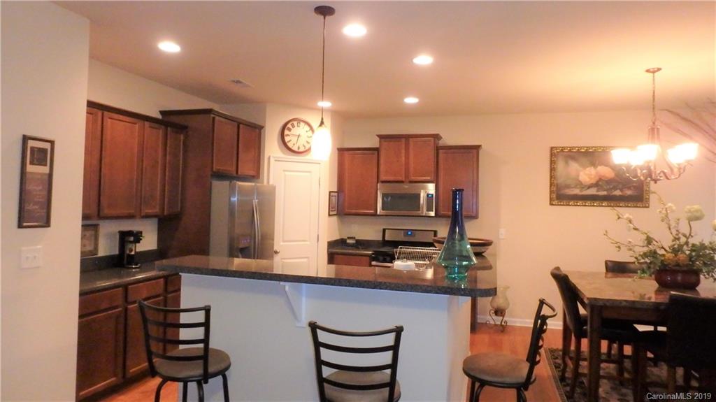 913 Rook Road Charlotte, NC 28216 - Photo 7 of 22 a kitchen with stainless steel appliances kitchen island granite countertop a stove a refrigerator a sink a dining table and chairs with wooden floor