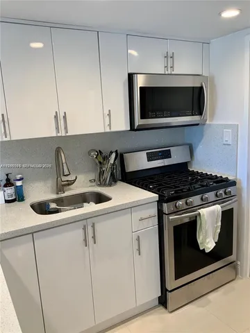 a kitchen with stainless steel appliances granite countertop a sink a stove and microwave