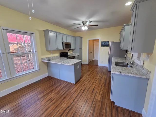 a kitchen with stainless steel appliances kitchen island granite countertop a sink cabinets and wooden floor