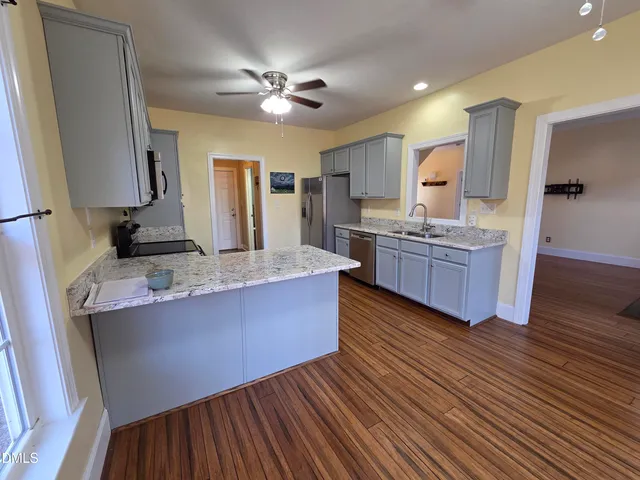 a large kitchen with stainless steel appliances granite countertop a lot of counter space and wooden floors