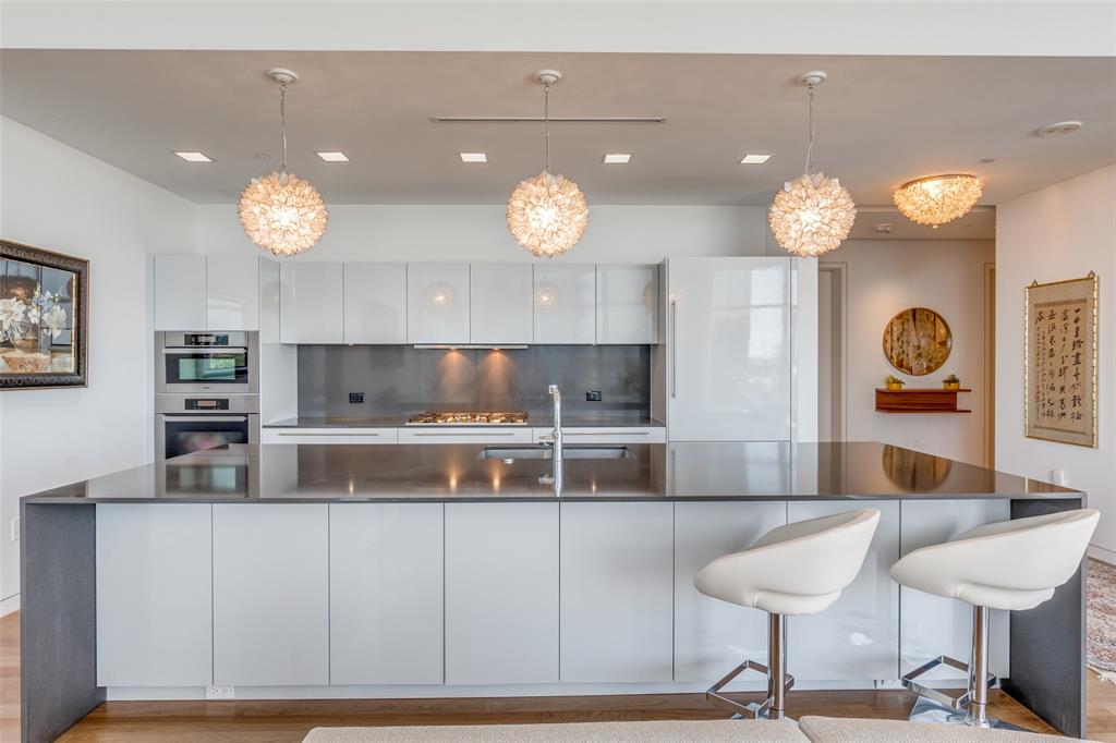 1918 Olive Street, Unit 701 Dallas, TX 75201 - Photo 14 of 40 a kitchen with kitchen island a chandelier and wooden floor