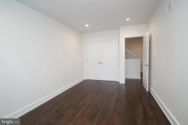 an empty room with wooden floor & closet
