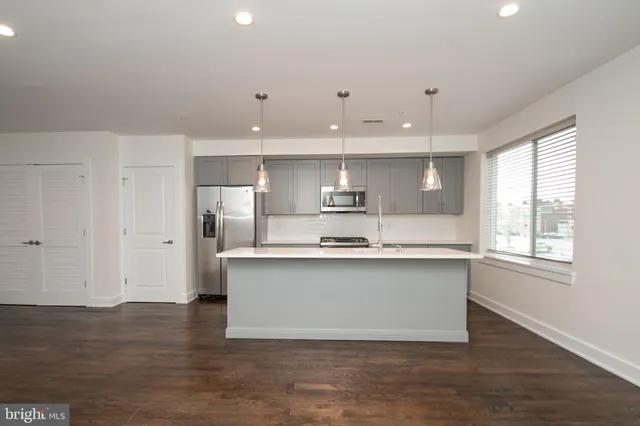 a large kitchen with stainless steel appliances a large counter top a sink and a window