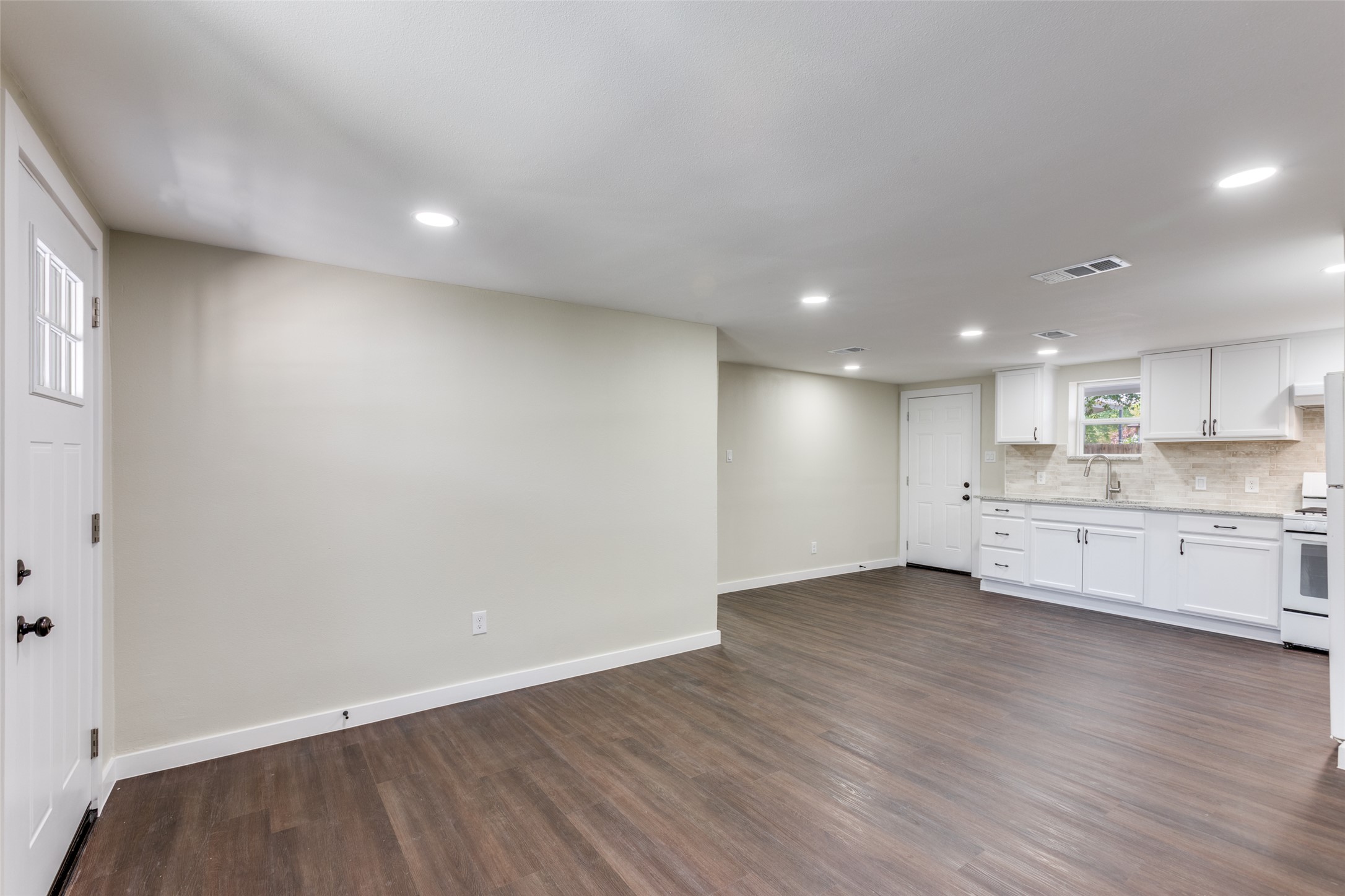 1118 Spur Street Austin, TX 78721 - Photo 21 of 21 The open-concept layout presents a cohesive kitchen and living space, featuring recessed lighting and durable wood flooring.