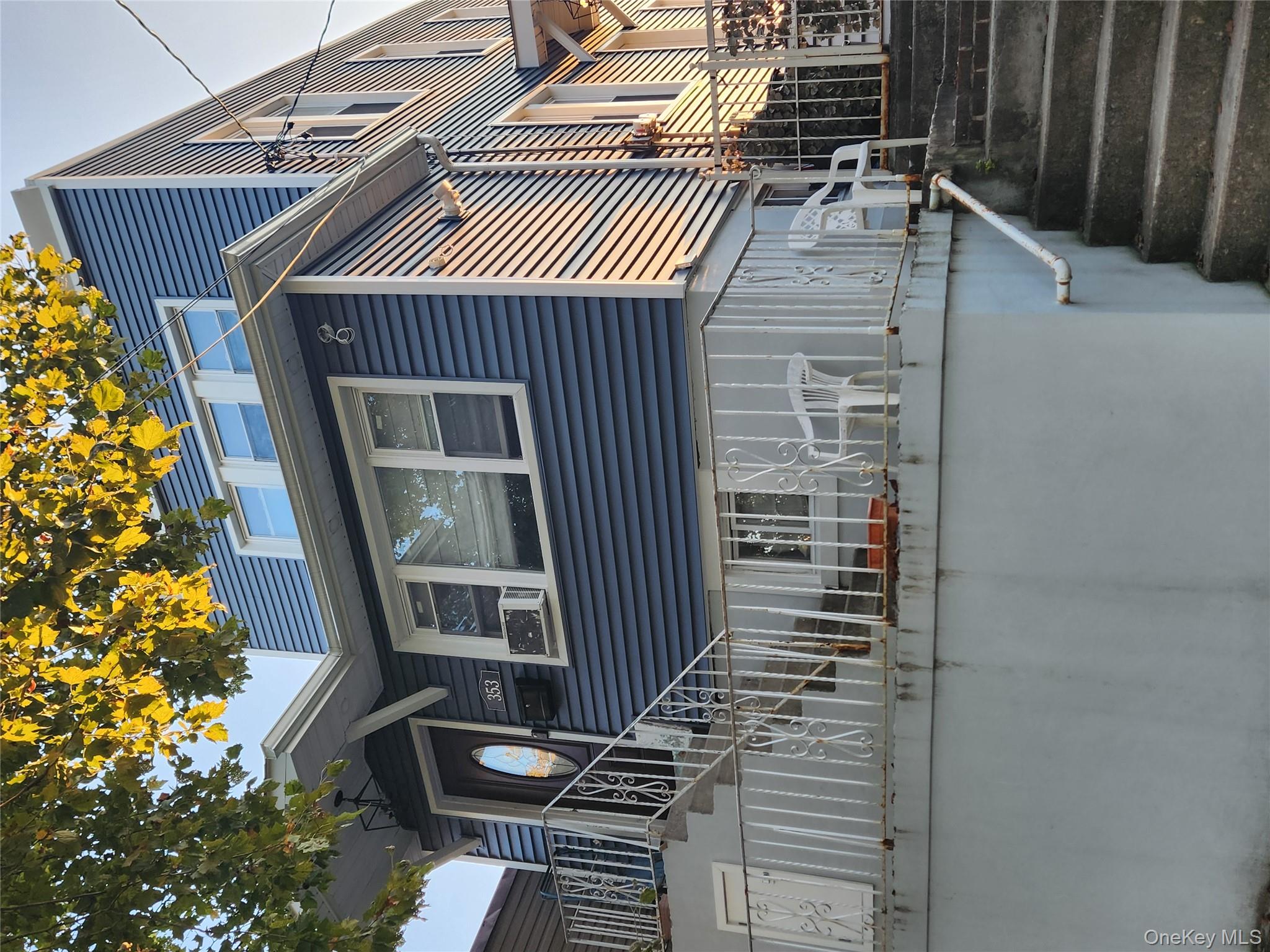 a front view of a house with stairs and a tree