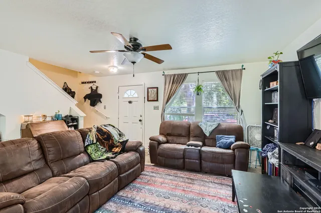 a living room with furniture a flat screen tv and a large window
