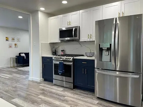 a kitchen with stainless steel appliances granite countertop a refrigerator a stove and a sink