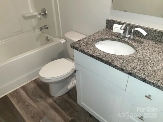 a bathroom with a granite countertop toilet a sink and bathtub