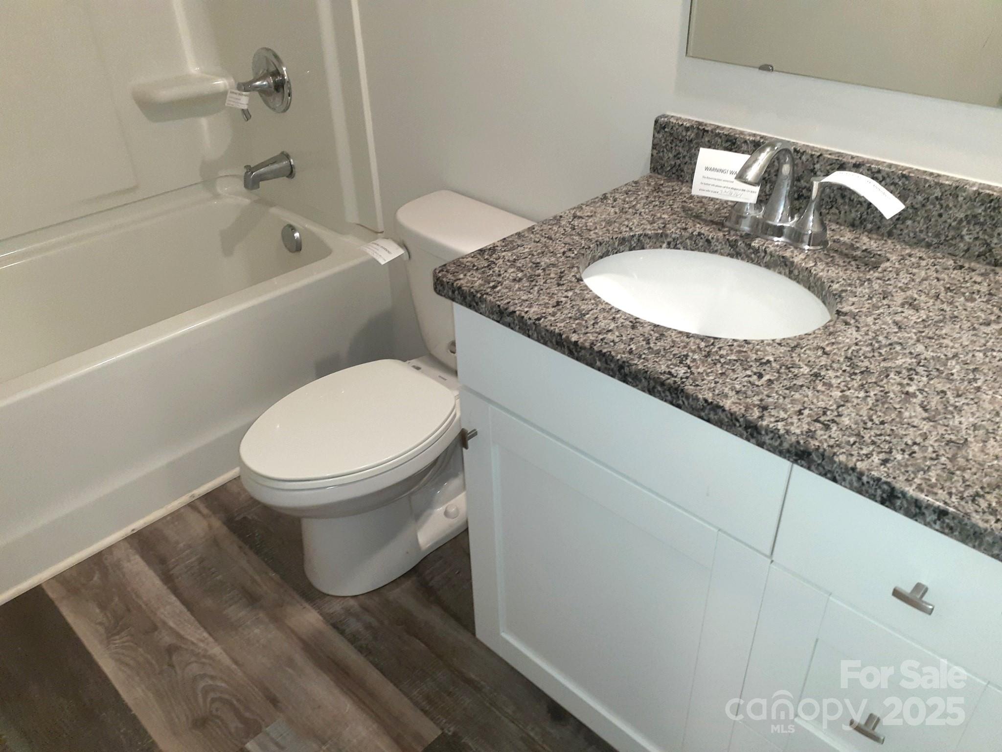 3944 Wade E Morgan Road Charlotte, NC 28269 - Photo 13 of 20 a bathroom with a granite countertop toilet a sink and bathtub