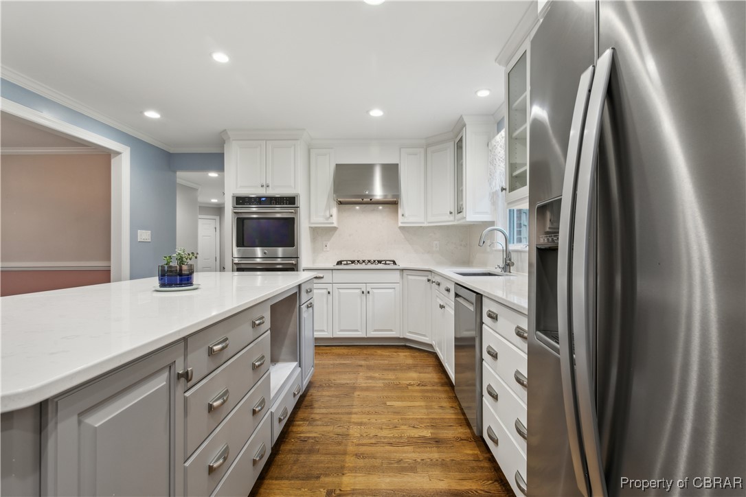 9300 Marlfield Road Gloucester, VA 23061 - Photo 19 of 50 Kitchen featuring appliances with stainless steel finishes, white cabinets, sink, tasteful backsplash, and hardwood / wood-style flooring