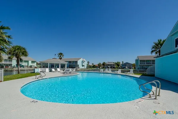 a view of a swimming pool with lawn chairs and a yard