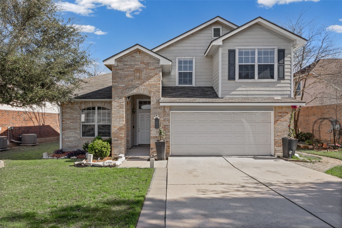View of front of property with a garage, a front lawn, driveway, brick siding, and a shingled roof