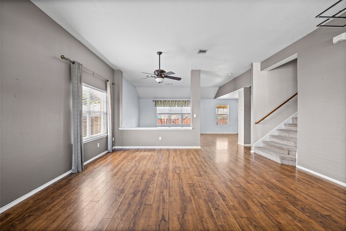1321 Bunratty Circle Pflugerville, TX 78660 - Photo 11 of 31 Unfurnished living room featuring dark wood-style flooring, stairs, and ceiling fan