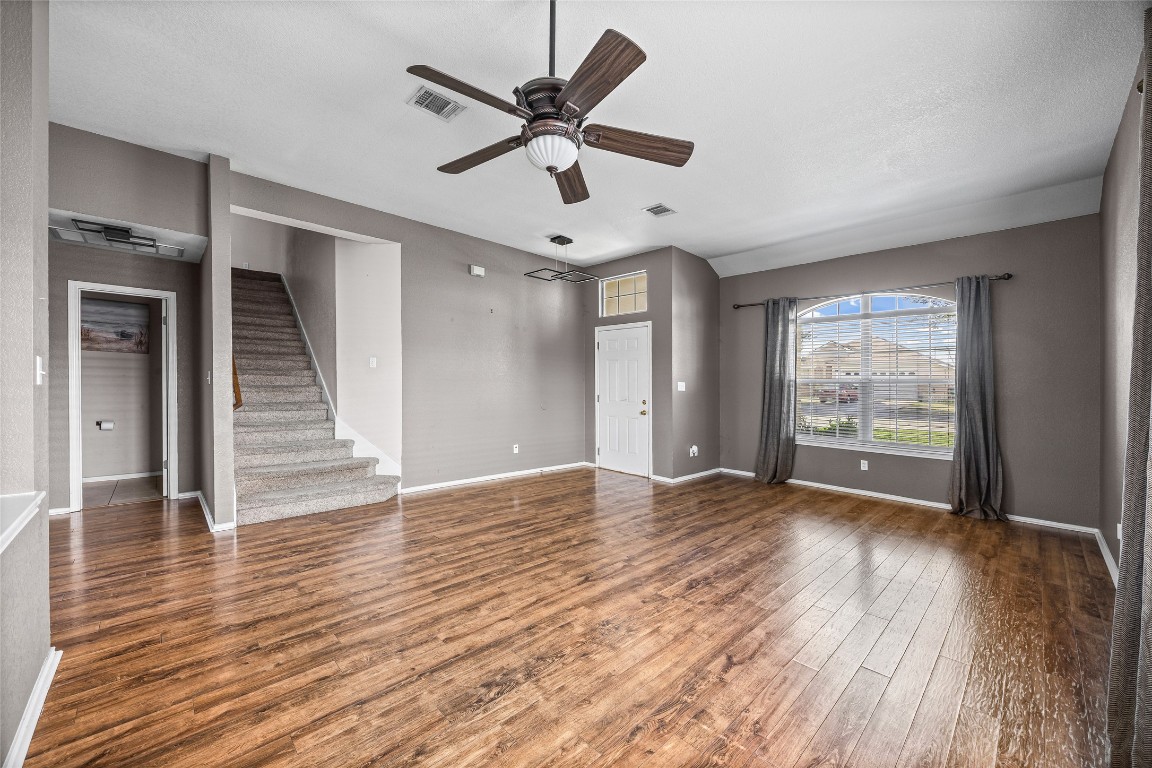 1321 Bunratty Circle Pflugerville, TX 78660 - Photo 12 of 31 Unfurnished living room featuring wood finished floors, a ceiling fan, and stairs