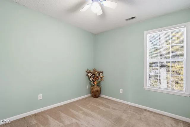 an empty room with windows and chandelier fan