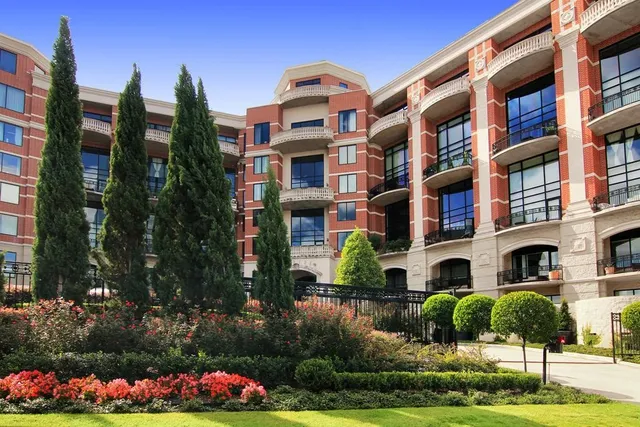 a front view of multi story residential apartment building with yard and sign board