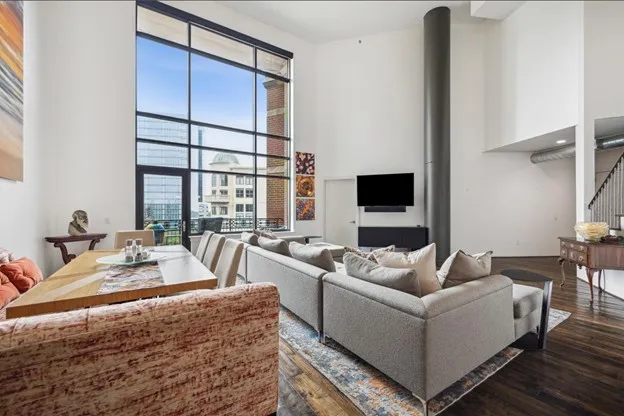 a living room with furniture a flat screen tv and a large window