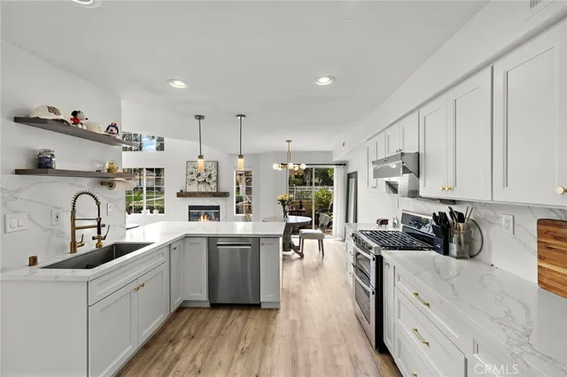 a kitchen with stainless steel appliances granite countertop a sink dishwasher stove refrigerator and cabinets with wooden floor