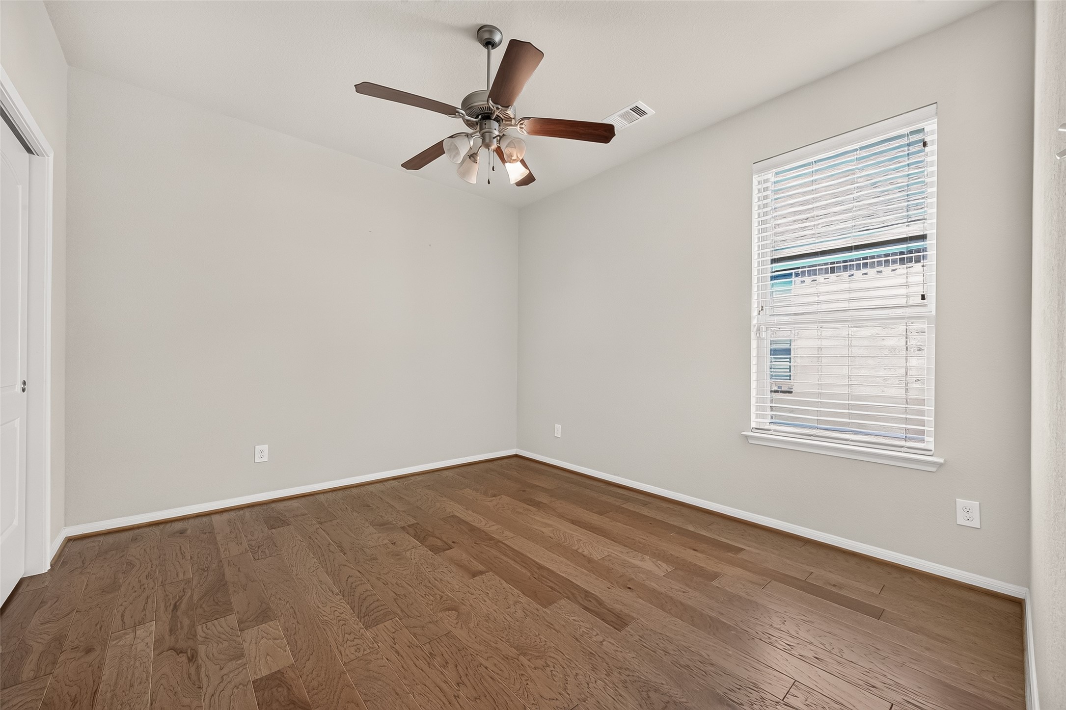 4910 Culver Lane Rosenberg, TX 77471 - Photo 37 of 50 This photo shows a bright, third bedroom with hardwood flooring, neutral walls, and a ceiling fan. There is a window with blinds allowing natural light, creating an ideal atmosphere.