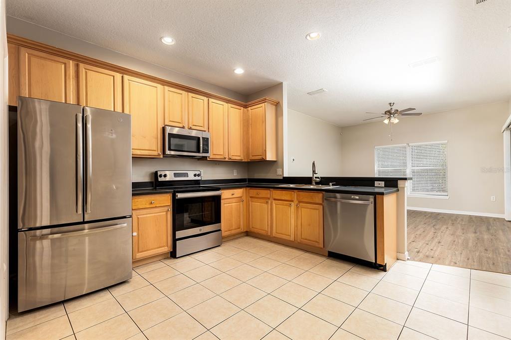 5255 Shale Ridge Trail Orlando, FL 32818 - Photo 9 of 24 a kitchen with granite countertop a refrigerator and a stove top oven