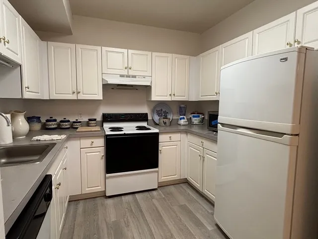 a kitchen with granite countertop white cabinets and white appliances