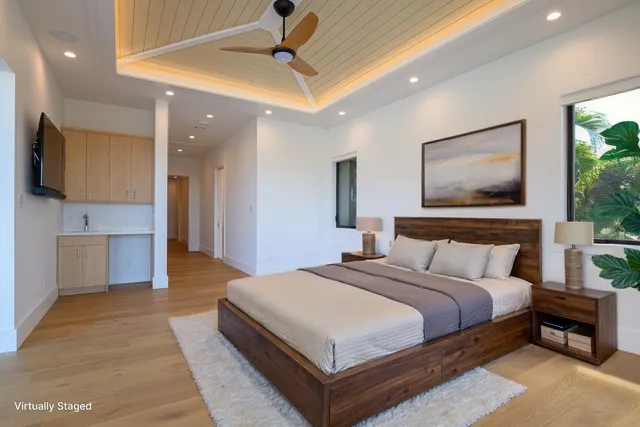 a spacious bedroom with a large bed a flat screen tv and a chandelier