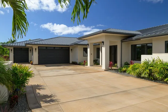 a view of yellow house with a yard and potted plants