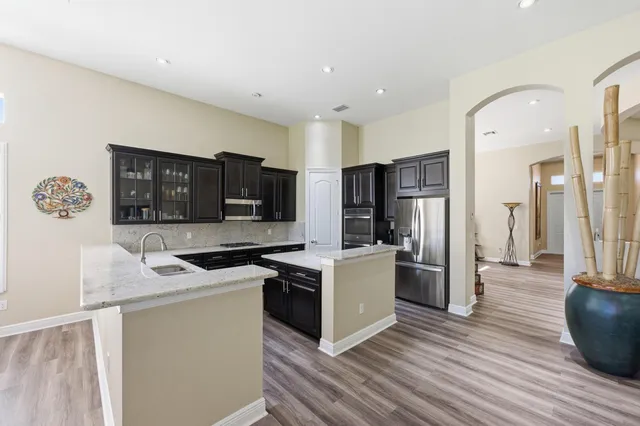 a kitchen with stainless steel appliances granite countertop a sink stove microwave and refrigerator