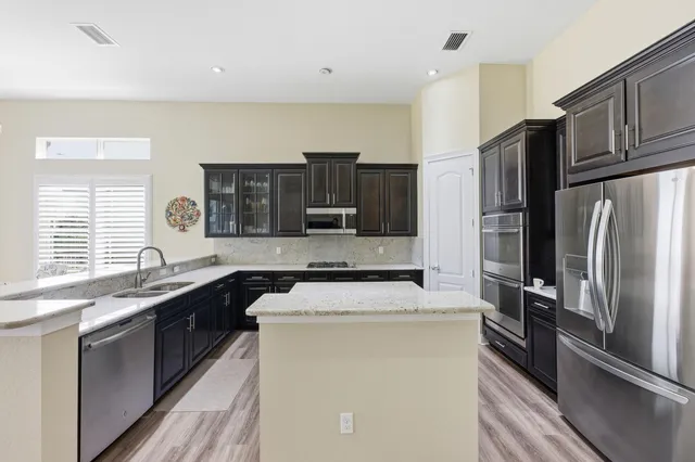 a kitchen with stainless steel appliances granite countertop a stove top oven a sink and a refrigerator