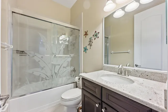 a bathroom with a granite countertop sink a toilet and shower