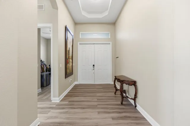 a view of a hallway with wooden floor and a bathroom