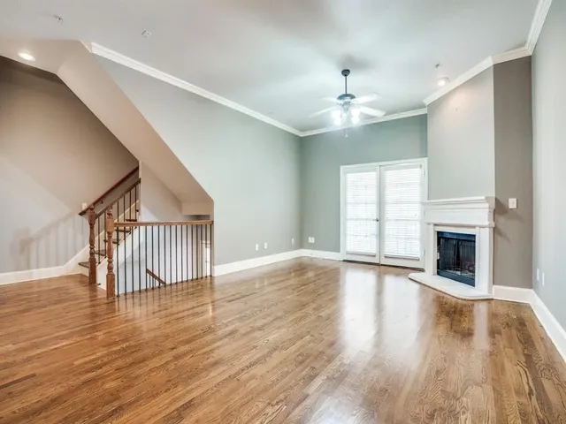 an empty room with wooden floor fireplace and windows