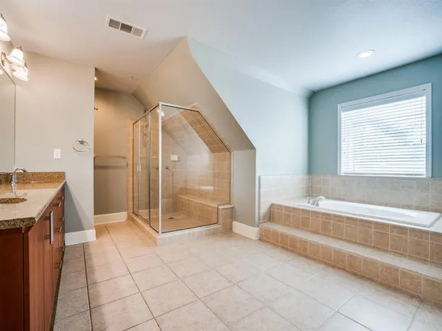 a spacious bathroom with a granite countertop sink and a bathtub