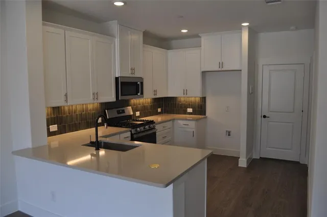 a kitchen with granite countertop a sink a stove and a refrigerator