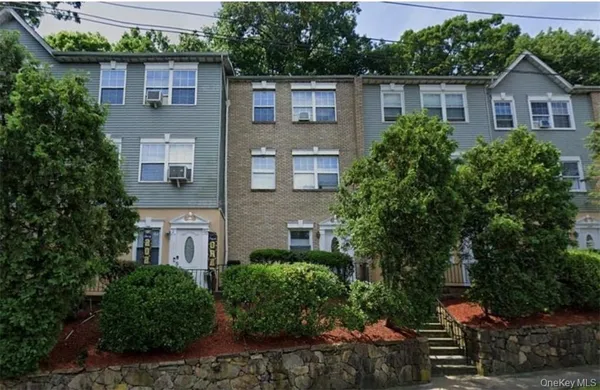 a front view of a house with a yard and potted plants